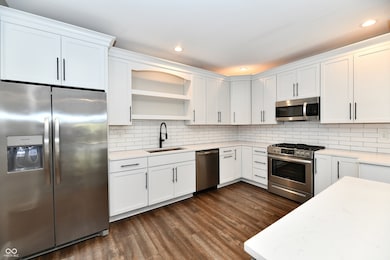 Kitchen with open shelves, white cabinetry, light stone counters, and recessed lighting