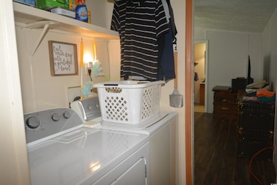 Laundry room with dark wood-type flooring, washing machine and dryer, and a textured ceiling