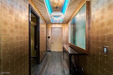 Hallway featuring a tray ceiling, dark wood finished floors, a chandelier, and tile walls