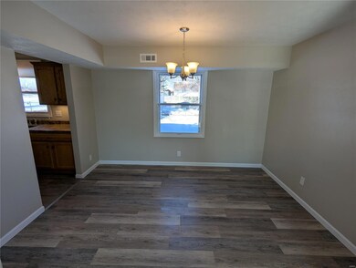 Unfurnished dining area featuring a notable chandelier and dark hardwood / wood-style floors