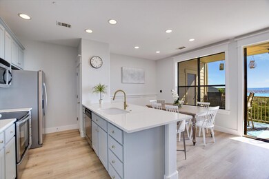 Kitchen with appliances with stainless steel finishes, a peninsula, recessed lighting, light wood finished floors, and light stone countertops