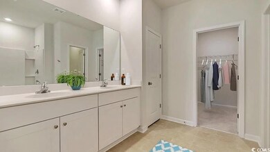 Full bath featuring double vanity, a walk in closet, baseboards, and tile patterned flooring