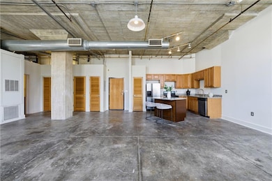 Kitchen featuring open floor plan, a high ceiling, a center island, concrete flooring, and appliances with stainless steel finishes
