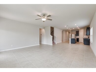 Unfurnished living room with stairs, a ceiling fa