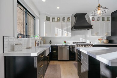 Kitchen featuring glass insert cabinets, white cabinets, dark cabinetry, custom range hood, and recessed lighting