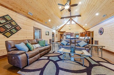 Living area with vaulted ceiling with beams, wood walls, ceiling fan, and wood ceiling