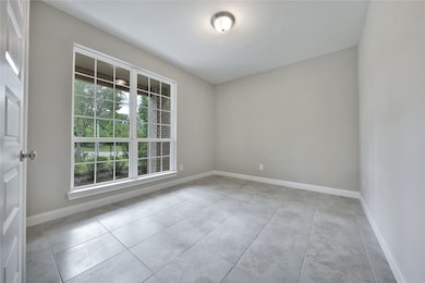 Ground-floor room with tiled flooring and a large window overlooking the front yard, perfect for an office or secondary bedroom.