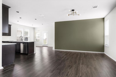 Kitchen featuring dark wood-type flooring, open floor plan, a chandelier, dishwasher, and light stone countertops