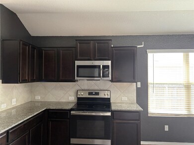 Kitchen with light stone counters, vaulted ceilin