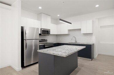 Kitchen featuring a center island, sink, tasteful backsplash, appliances with stainless steel finishes, and light hardwood / wood-style flooring