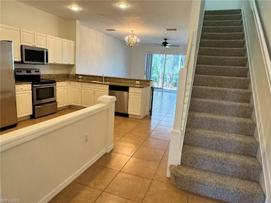 Kitchen featuring stainless steel appliances, white cabinets, light tile patterned flooring, decorative light fixtures, and recessed lighting