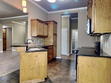 Kitchen featuring electric range, a peninsula, dark tile patterned floors, backsplash, and ornamental molding