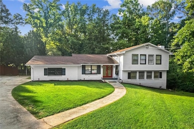 Split level home featuring brick siding, concrete driveway, french doors, and a front yard