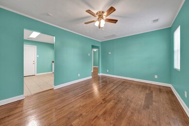 Unfurnished room featuring ornamental molding, a ceiling fan, and wood finished floors