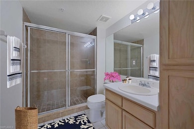 Full bathroom with toilet, vanity, a shower stall, tile patterned flooring, and a textured ceiling