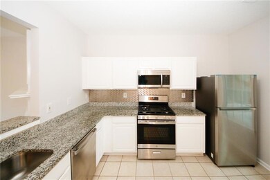 Kitchen featuring appliances with stainless steel finishes, backsplash, light stone counters, and white cabinets