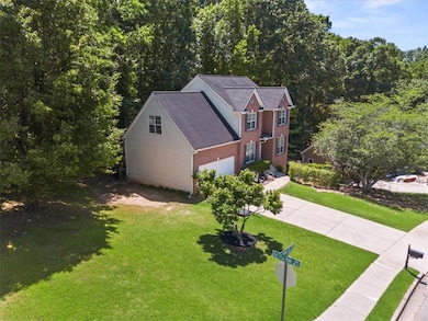 View of front of property featuring a front yard, driveway, and a view of trees