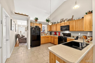 Kitchen with decorative light fixtures, black appliances, light countertops, high vaulted ceiling, and light tile patterned flooring