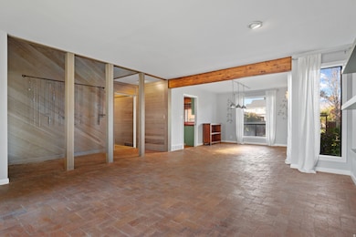 living room featuring brick floors, beam ceiling, and wood walls