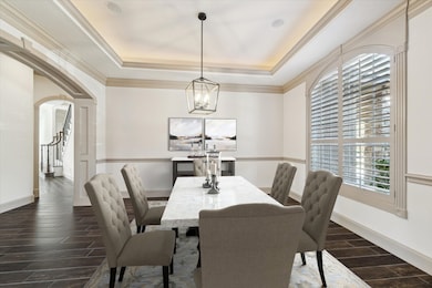 The large dining room is just off the foyer with large casing doorways, large windows with shutters and tray ceilings. Digitally staged.
