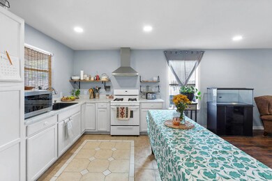 Kitchen featuring white range with gas cooktop, open shelves, wall chimney range hood, recessed lighting, and white cabinets
