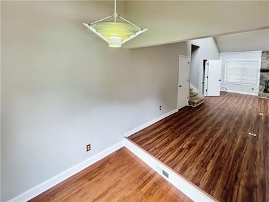 Unfurnished room featuring wood finished floors, stairs, and vaulted ceiling