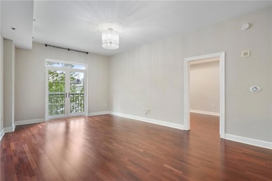 Empty room featuring a chandelier, dark wood-style flooring, and baseboards