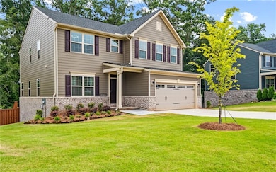 View of front of property featuring a garage, concrete driveway, and brick siding