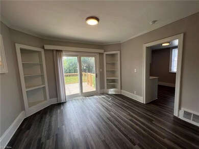 Wood floored empty room with built in shelves and ornamental molding