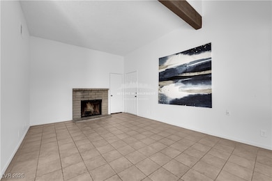 Unfurnished living room featuring a fireplace, tile patterned floors, and beamed ceiling
