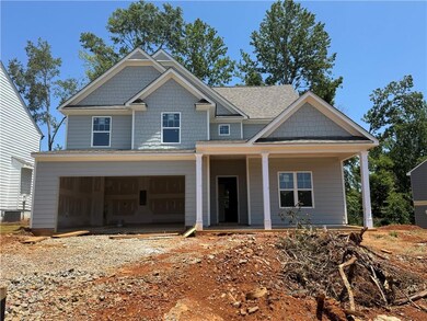 View of front of house with covered porch, dirt driveway, an attached garage, and roof with shingles