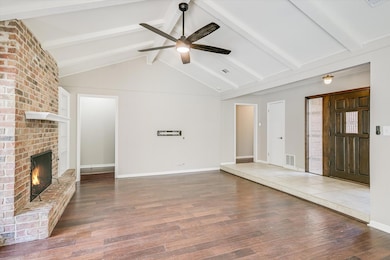 Unfurnished living room with wood finished floors, a brick fireplace, and ceiling fan