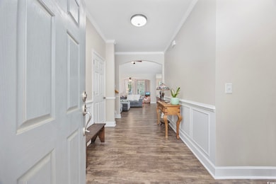 Entryway with ornamental molding, arched walkways, and wood finished floors