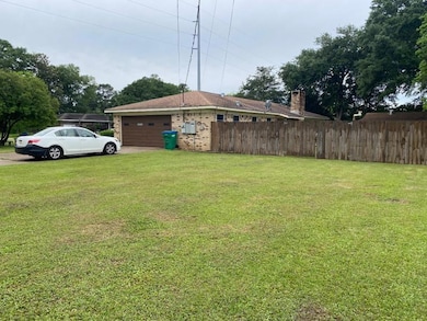 View of yard with fence, a garage, and driveway