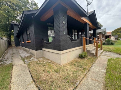 View of side of property featuring brick siding, a lawn, and a porch