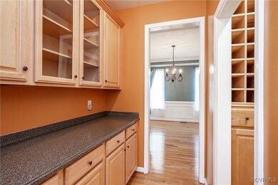 Kitchen featuring light brown cabinetry, light wood-type flooring, a wainscoted wall, a chandelier, and a decorative wall