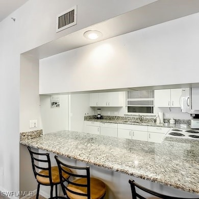 Kitchen with white appliances, visible vents, a pe
