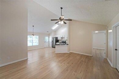 Unfurnished living room featuring a ceiling fan, light wood-style floors, a textured ceiling, a chandelier, and high vaulted ceiling