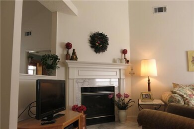 Living room has gas log fireplace with vaulted ceilings and ceiling fan for open airy feel.
