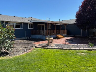 Back of house with a patio, a lawn, a wooden deck, and a shingled roof