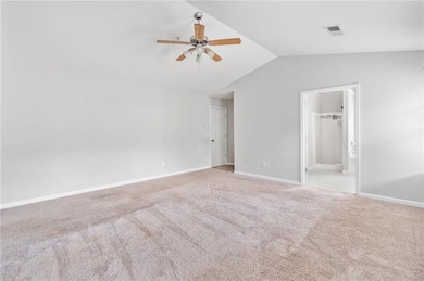 Carpeted spare room with vaulted ceiling, ceiling fan, and baseboards