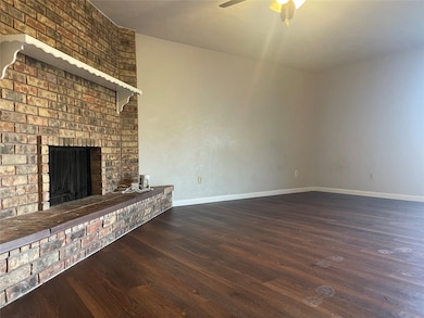 Unfurnished living room featuring dark wood-style floors, a fireplace, and a ceiling fan