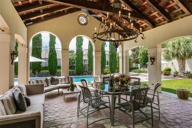 Spectacular covered loggia with vaulted and beamed ceiling, fabulous wrought iron chandelier, and views to the backyard oasis.