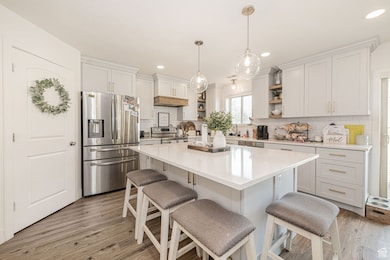 Kitchen with appliances with stainless steel finishes, a kitchen breakfast bar, a center island, light wood-style flooring, and recessed lighting