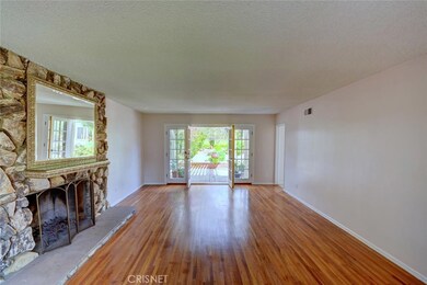 Living room warmed by fireplace, french doors open to yard and view, refinished wood floors flow throughout  most of the home