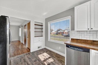Kitchen with appliances with stainless steel finishes, wood counters, white cabinetry, and dark wood-style floors