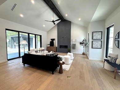 Living room featuring a ceiling fan, high vaulted