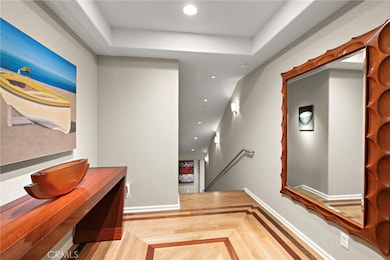 Enter into the foyer with gorgeous wood flooring and art lighting leading you down the stairs.