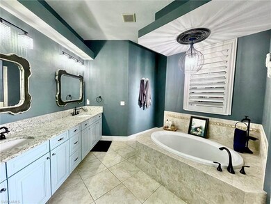 Bathroom with tile patterned flooring, a garden tub, double vanity, and a chandelier