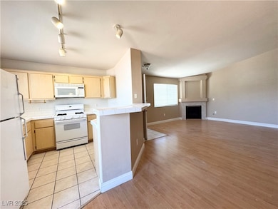 Kitchen featuring white appliances, tile counterto